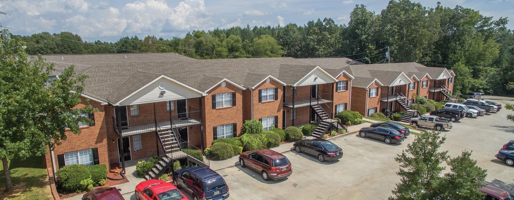 brick apartments with cars parked in front of it